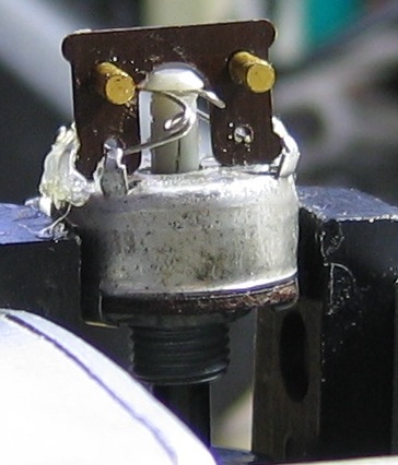 Side view of contact carrier on edge on back of pot, held by hot glue on its edges. Springs and contactgs in place.