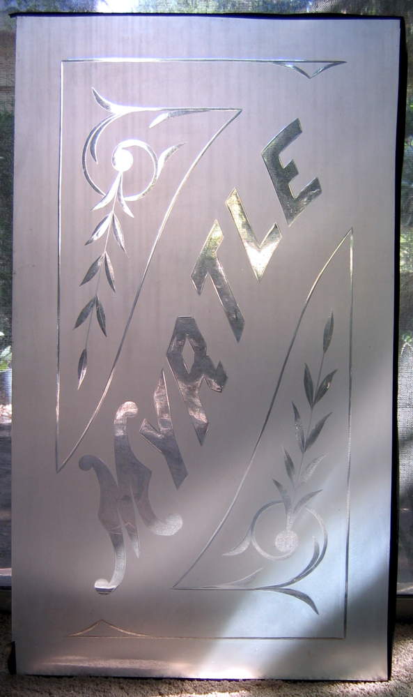 Pretty glass pane with the word “Myrtle” and some decorations etched in.