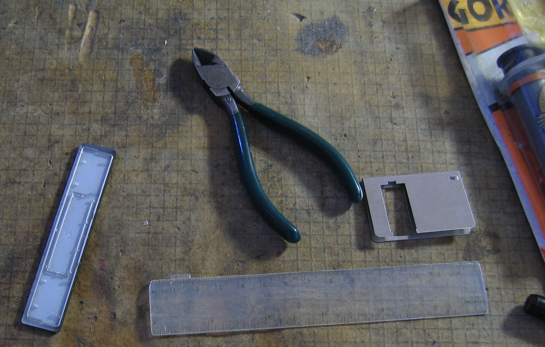 Approx. 2 mm square metal pieces cut by diagonal cutters from floppy disk shutter, one piece against ruler edge